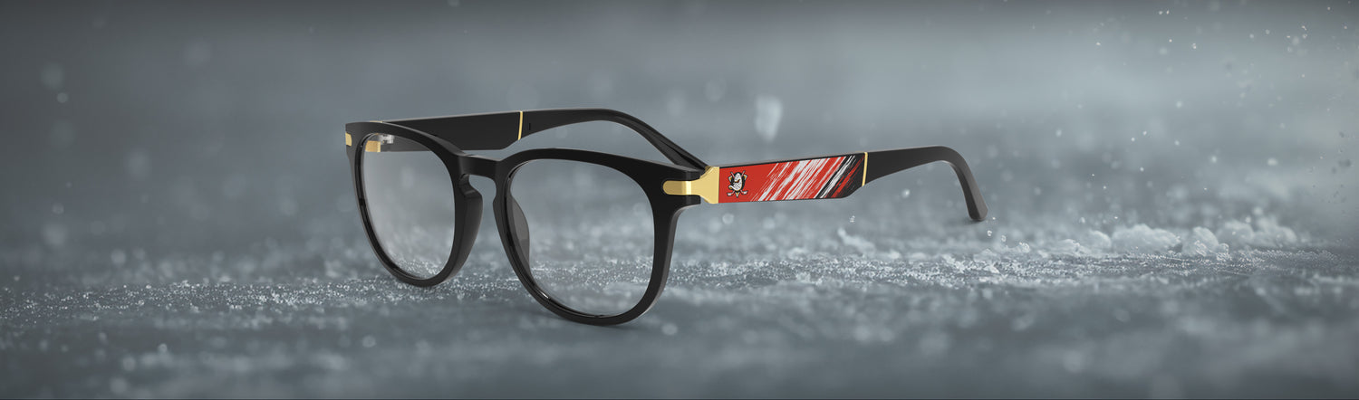 Black eyeglasses with a red and gold band on a gray background