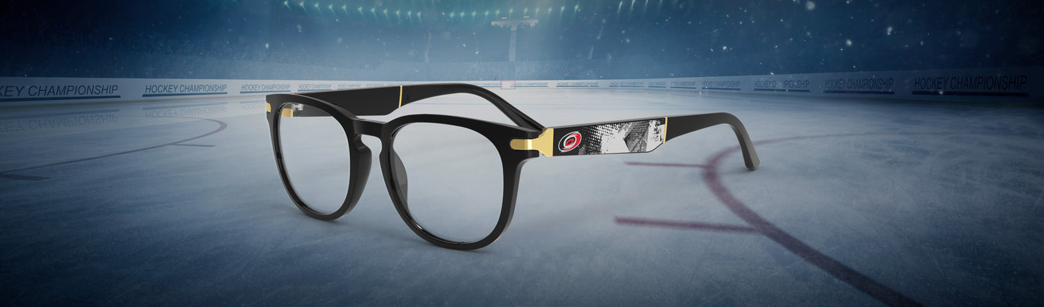 Allegiant glasses with temple blade showing Carolina Hurricanes logo against a black abstract design in a hockey rink setting.