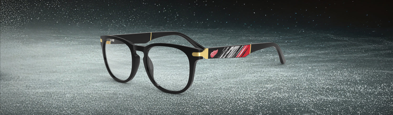 Allegiant glasses with temple blade showing Detroit Red Wings logo against a black and red abstract design in a hockey rink setting.