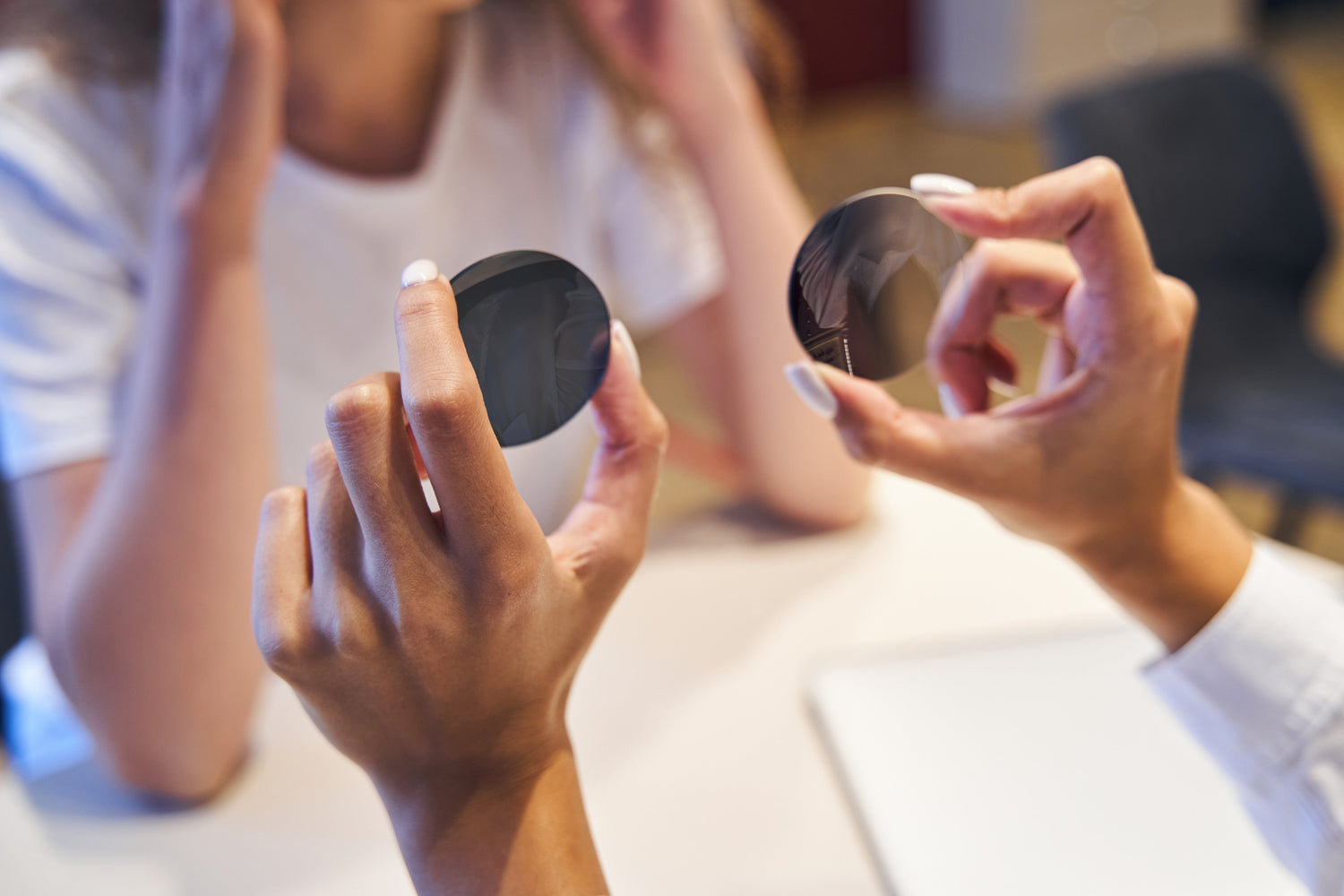 Optician compares two round lenses with different tint for eyewear