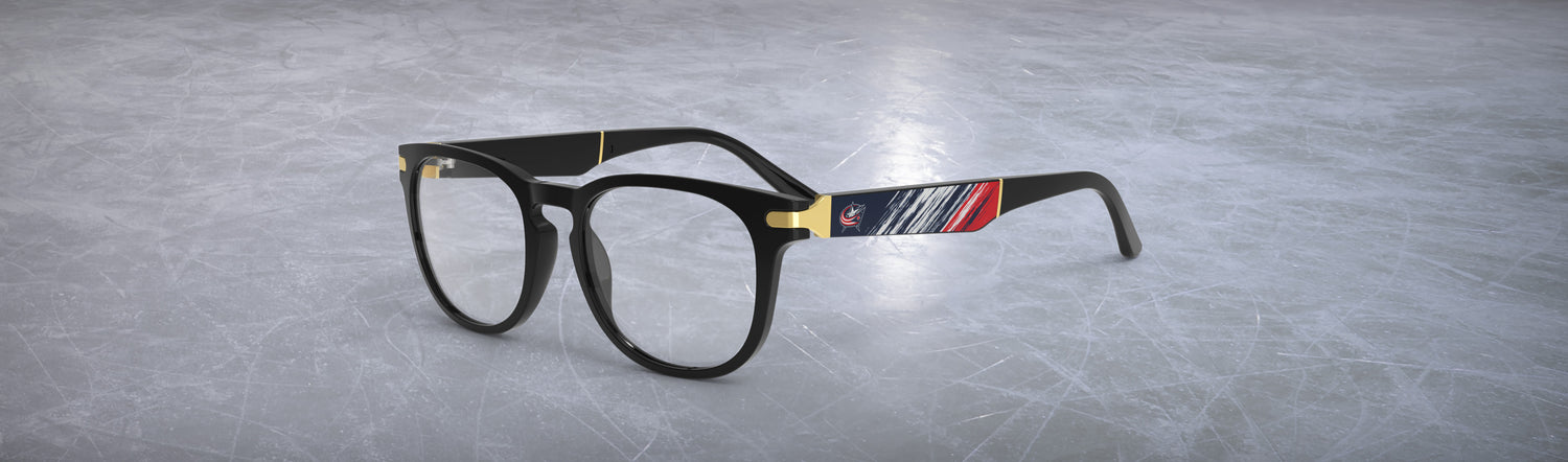 Black-framed Allegiant eyeglasses with a Columbus Blue Jackets logo on the temple blade with an abstract blue, red, and white design on an ice hockey rink background.